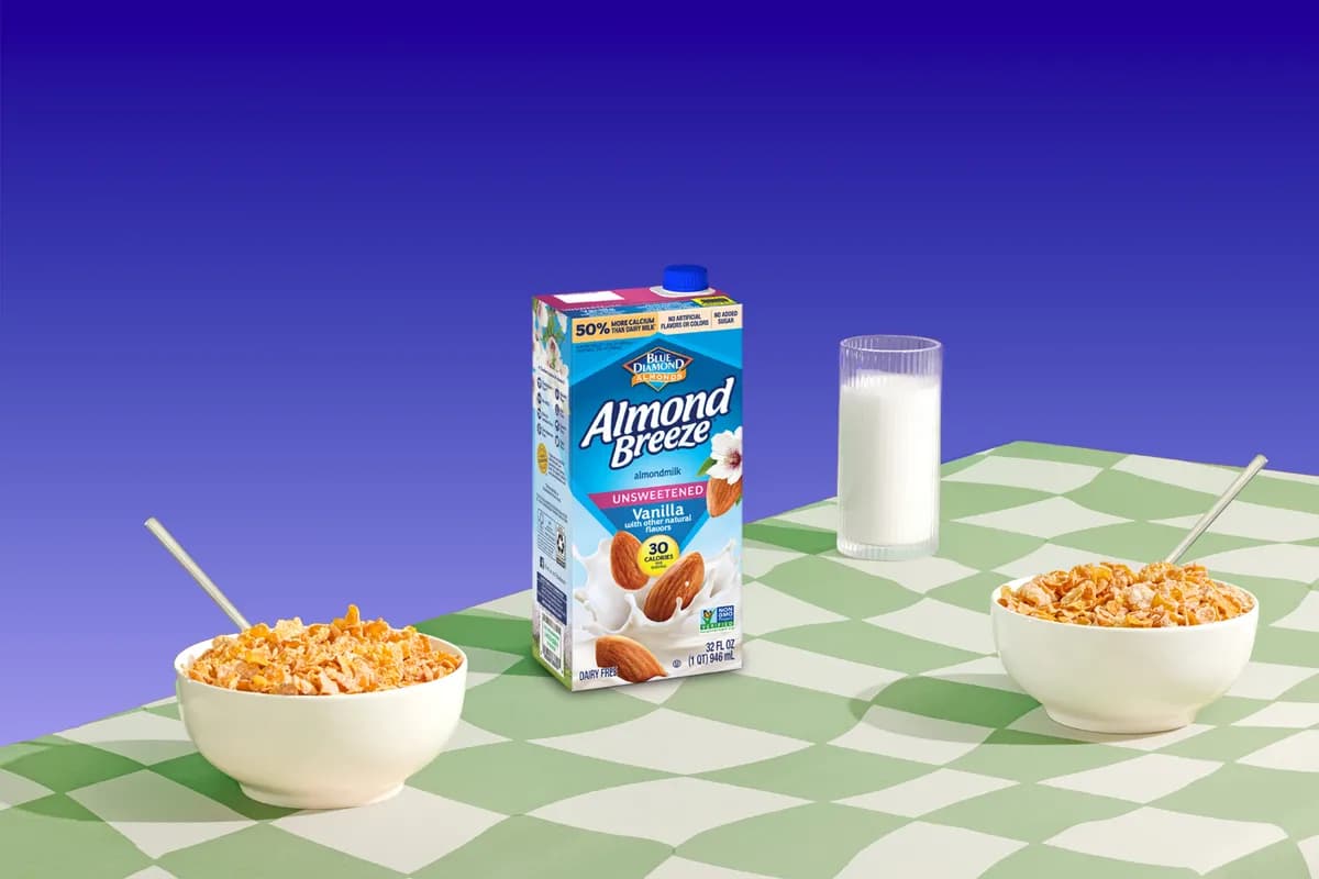 Shelf Stable Almond Breeze almond milk carton and bowls of cereal on a table.