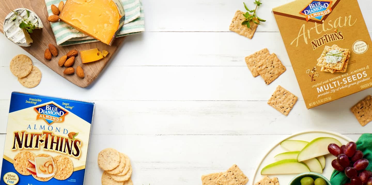 Nut-Thins crackers, cheese, and fruit on a table.